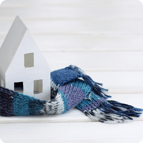 Small house model wrapped in a warm scarf on a white surface