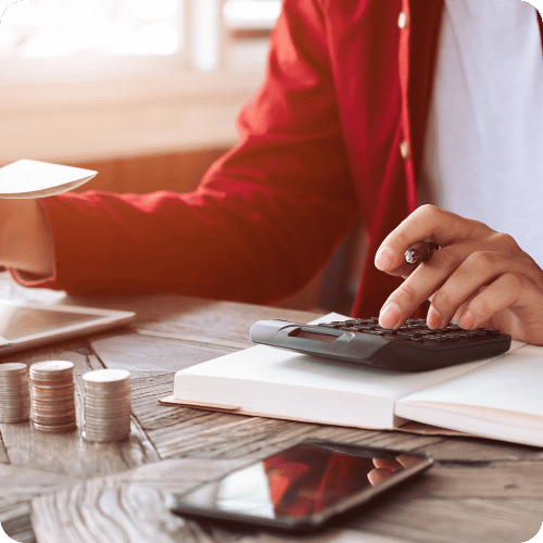 Person calculating home energy costs with calculator and coins on a desk