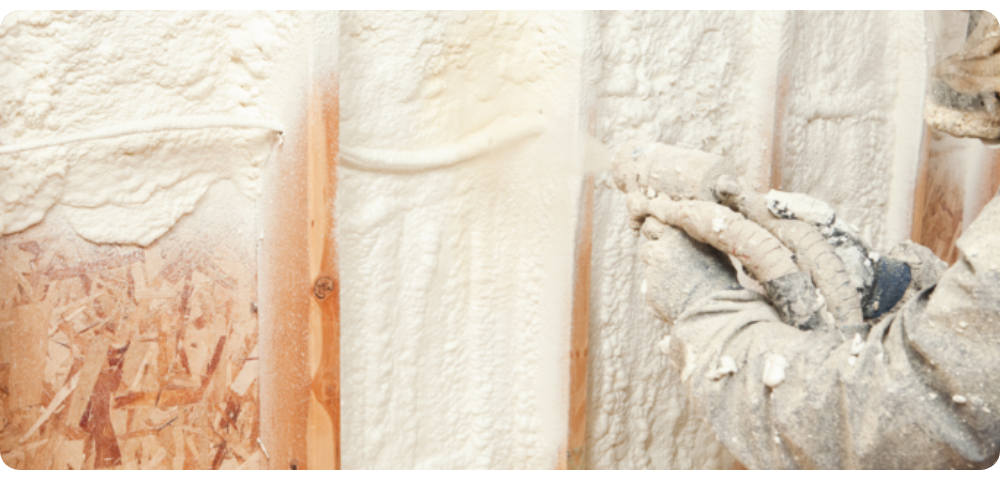 Builder spraying foam on a wall to seal it