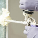 Close-up of a foam spray gun spraying foam to seal a wall