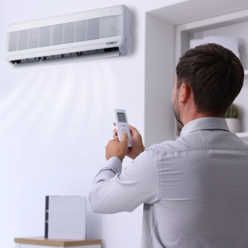 Man adjusting air conditioner with remote for home heating and cooling efficiency